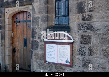 Außen Kirche Büro, hölzerne Eingangstür Nahaufnahme (Bandscharniere) Steinwand & Schnee auf Tafel - All Saints Parish Church, Ilkley, England, Großbritannien. Stockfoto