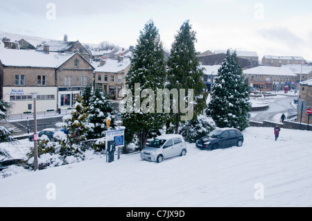 Verschneite Winterstadt (Autos geparkt, schneebedeckte ruhige Parkplätze, Pay & Display Ticketautomat, Geschäfte, Straßen) - Baildon, West Yorkshire, England, Großbritannien Stockfoto