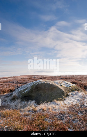 Malerische Winteransicht hoch auf Mooren (verlassene Berglandschaft, großer Felsbrocken, frostbedeckte Heidepflanzen, tiefblauer Himmel) - Burley Moore, Yorkshire, Großbritannien. Stockfoto