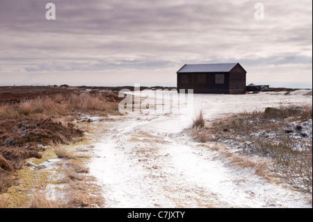 Kalter Schneeblick im Winter auf der Strecke zur Holzschießhütte hoch auf exponierter schneebedeckter Heidemoorfläche - Burley Moore, West Yorkshire, England, Großbritannien. Stockfoto