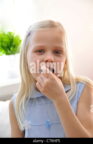 Junges Mädchen, 6, mit einem blauen Kleid Essen einen donut Stockfoto
