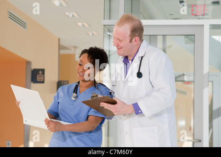 Männlichen Arzt ein medizinisches Gutachten mit einer Krankenschwester zu diskutieren Stockfoto