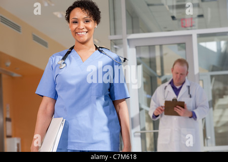 Porträt von eine Krankenschwester mit einem männlichen Arzt hinter ihr stand lächelnd Stockfoto
