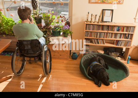 Frau mit Multipler Sklerose in einem Rollstuhl im Gespräch auf ein Mobiltelefon mit Hundesitting-Service in ihrer Nähe Stockfoto