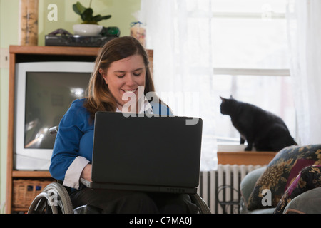 Geschäftsfrau mit Spina Bifida in einem Rollstuhl mit ihrem Laptop zu Hause Stockfoto