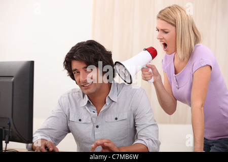 ein Mann tun, Computer und eine Frau auf ihn mit einem Megaphon schreien Stockfoto