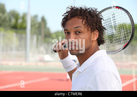 Tennisspieler, die Abhaltung von Schläger über die Schulter während Spiel auf Hartplatz Stockfoto