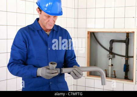 Handwerker, die zwei Teile des Rohres zusammenpassen Stockfoto