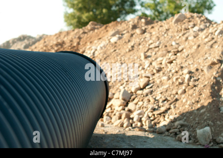 Schwarze Rohre und haufenweise Sand im Hintergrund. Stockfoto