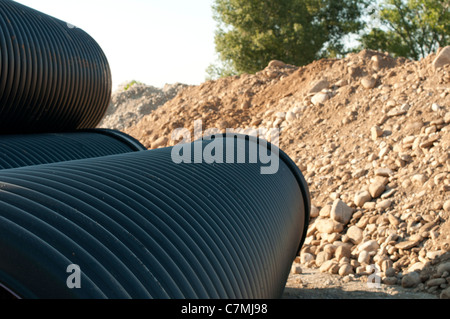 Schwarze Rohre und haufenweise Sand im Hintergrund. Stockfoto