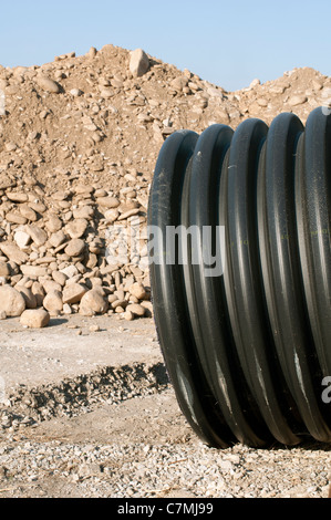 Schwarze Rohre und haufenweise Sand im Hintergrund. Vertikales Bild Stockfoto