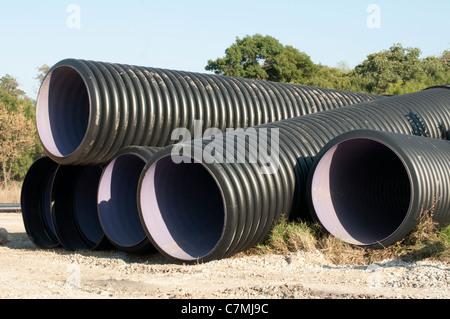 Schwarze Rohre und haufenweise Sand im Hintergrund. Stockfoto