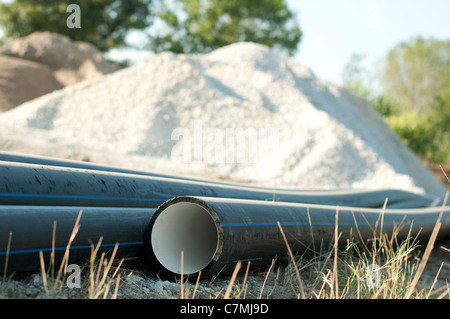 Schwarze Rohre und haufenweise Sand im Hintergrund. Stockfoto