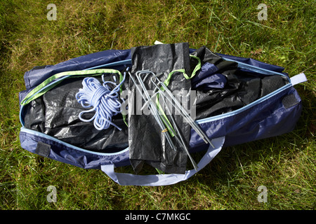 Beutel mit Heringen Auspacken ein kleines Zelt in einem Beutel auf dem Rasen liegend Stockfoto