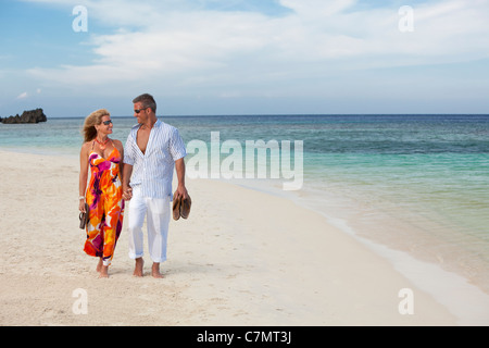 Paare, die Hand in Hand entlang tropischen Strand Stockfoto