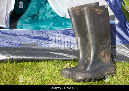 schmutzige Wellington boots vor einem offenen Zelttür liegen Stockfoto