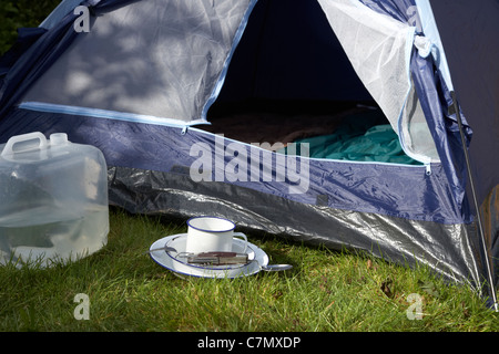 Wasser Behälter Weissblech Cup und camping Werkzeug Utensilien vor die offene Tür eines Zeltes Stockfoto