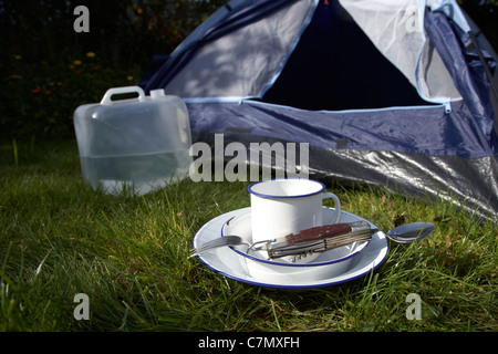 Wasser Behälter Weissblech Cup und camping Werkzeug Utensilien vor die offene Tür eines Zeltes Stockfoto