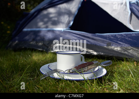 Weissblech Cup und camping-Werkzeug-Utensilien vor die offene Tür eines Zeltes Stockfoto