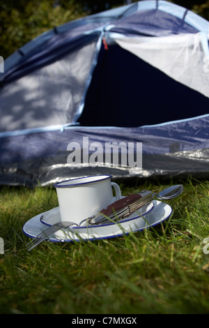 Weissblech Cup und camping-Werkzeug-Utensilien vor die offene Tür eines Zeltes Stockfoto