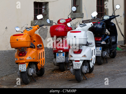 Vier Vespa Motorroller geparkt auf dem Dorfplatz in Lamole, Toskana. Stockfoto