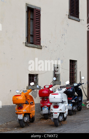 Vier Vespa Motorroller geparkt auf dem Dorfplatz in Lamole, Toskana. Stockfoto