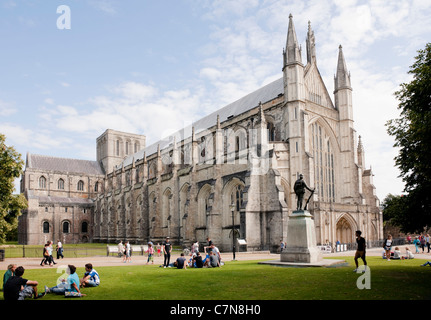 Kathedrale von Winchester, Hampshire, England mit Kriegerdenkmal an einem sonnigen Sommertag mit Menschen entspannen auf Cathedral Close Stockfoto
