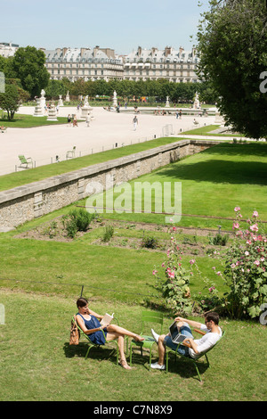 Mann mit einem Laptop mit eine Frau liest eine Zeitschrift im Garten Jardin des Tuileries, Paris, Ile de France, Frankreich Stockfoto