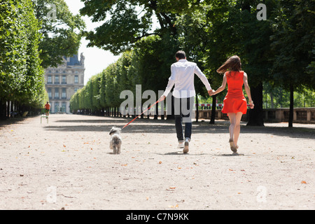 Paar läuft in einem Garten mit einem Welpen, Terrasse De l ' Orangerie, Jardin des Tuileries, Paris, Ile de France, Frankreich Stockfoto
