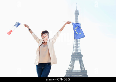 Frau hält eine Fahne der Europäischen Union und eine französische Flagge mit dem Eiffelturm im Hintergrund, Paris, Ile de France, Frankreich Stockfoto