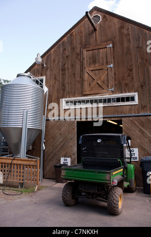 Eine braune hölzerne Scheune mit großen Körnern Silo Tank außerhalb. Stockfoto