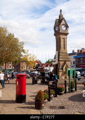 Die Stadt-Uhr und einen leuchtend roten Briefkasten auf dem Marktplatz in Thirsk North Yorkshire UK Stockfoto