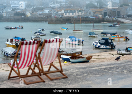 Liegestühle am Strand von St. Ives, Cornwall. Große englische Sommer Urlaub Szene Boote auf dem Meer. Stockfoto