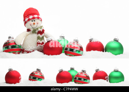 Weihnachts-Dekoration mit Schneemann und Kugeln auf Schnee. Stockfoto
