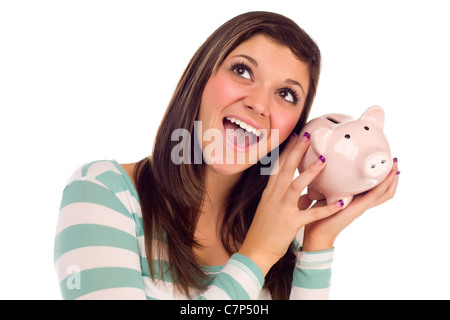 Lächeln auf den Lippen ziemlich ethnische weibliche Tagträumen und Holding rosa Sparschwein zu ihrem Ohr, Isolated on White Background. Stockfoto