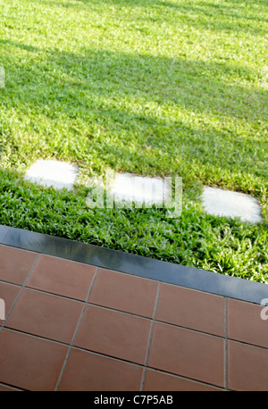 geflieste Terrasse und üppigen grünen Rasen mit Stein Flagge Trittsteine, vertikale Porträt Ernte Bereich und Kopie Raum Stockfoto