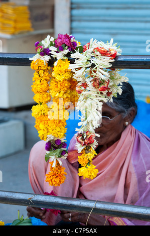 Alte indische Frau Blumengirlanden für hindu religiösen Angebote auf der Straße zu verkaufen. Indien Stockfoto