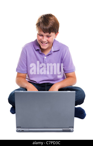 Foto eines 11 Jahre alten Schule Jungen Lachen als sieht er vor seinem Laptop-Bildschirm, isoliert auf einem weißen Hintergrund. Stockfoto