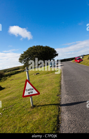 Rinder-Raster-Zeichen und geparkte Autos vor einem blauen Himmel auf Dartmoor, Devon, UK Stockfoto