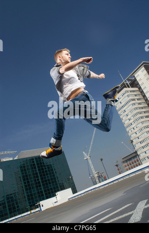 Mann springt auf städtischen Dach Stockfoto