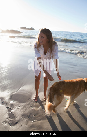 Frau Petting Hund am Strand Stockfoto