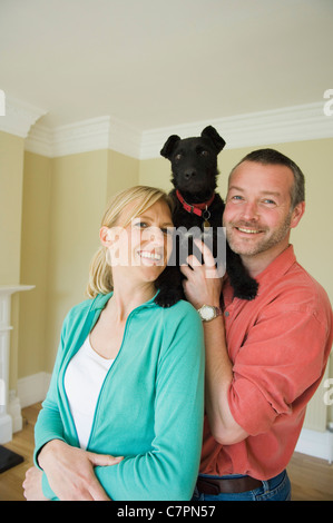 Lächelnde paar mit Hund im neuen Zuhause Stockfoto