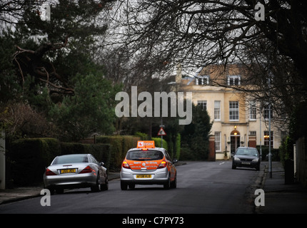 BSM Instruktoren Steuerwagen rundet einen stationäre Mercedes in einem in der Regel Vorort Straße in England UK Stockfoto