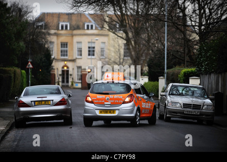 BSM Instruktoren Steuerwagen kehrt um eine stationäre Mercedes in einem in der Regel Vorort Straße in England UK Stockfoto