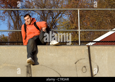 Ein junger Mann an der Spitze einer Skateboard-Rampe posiert. Stockfoto