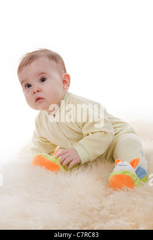 Schönen braunen Augen Baby sitzt liegt auf weißem Fell Stockfoto