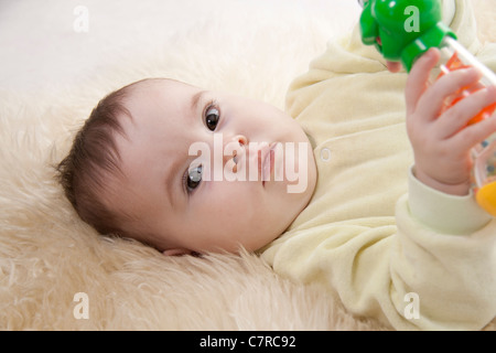 Schönen braunen Augen Baby liegt auf weißem Fell Stockfoto