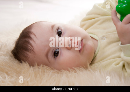 Schönen braunen Augen Baby liegt auf weißem Fell Stockfoto