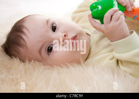 Schönen braunen Augen Baby liegt auf weißem Fell Stockfoto