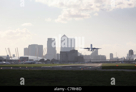 Eine Boeing 318 Flugzeuge abheben von London City Airport mit Blick auf die City of London im Hintergrund Stockfoto